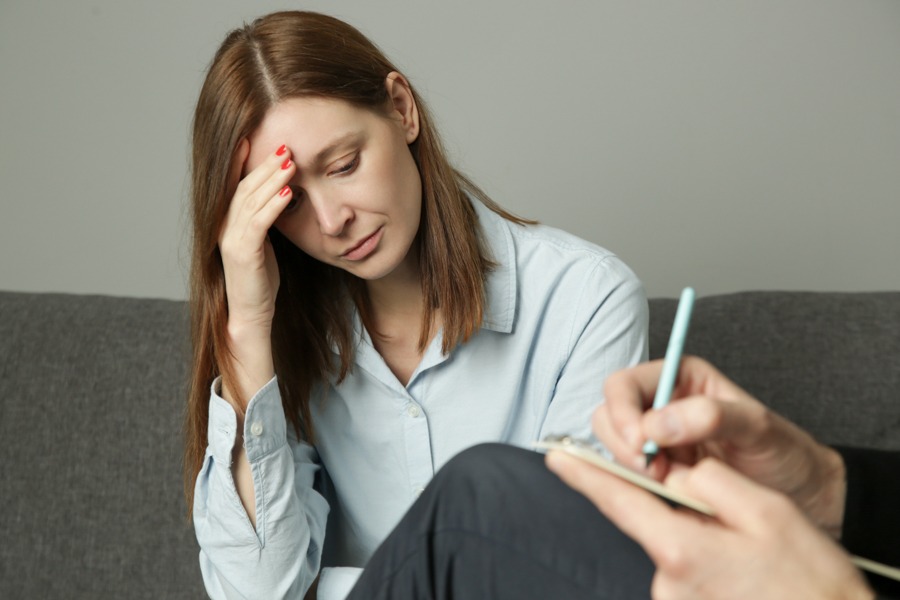 a woman with hand on face sad sitting in therapy